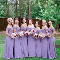 a group of women standing next to each other wearing purple dresses and holding bouquets