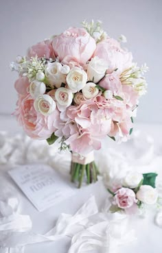 a bouquet of pink and white flowers sitting on top of a table next to a card