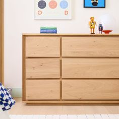 a wooden dresser sitting next to a wall with pictures on it