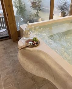 a hot tub filled with lots of water next to a glass of wine and fruit