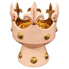 a pink and gold crown on top of a white stand with lots of gold studs