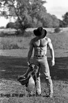 a shirtless man standing next to a sheep wearing a cowboy's hat and boots