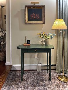 a room with a table, lamp and pictures hanging on the wall above it's doorway