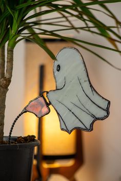 a glass ghost hanging from the side of a potted plant