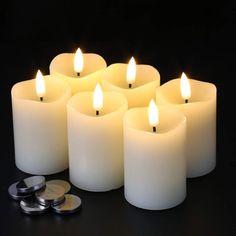 several lit candles and some coins on a black surface