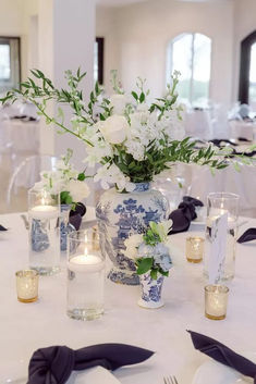 a vase filled with white flowers sitting on top of a table covered in blue and white napkins