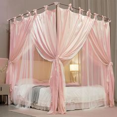 a pink canopy bed with sheer curtains on it