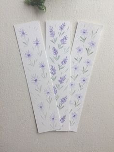 three bookmarks with watercolor flowers on them next to a flower potted plant