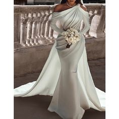 a woman in a white dress is posing for a photo with her bouquet on her wedding day