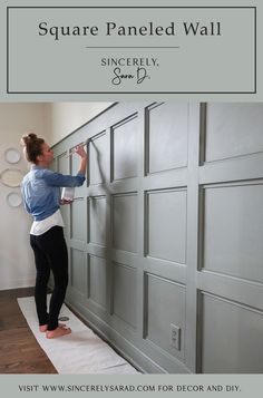 a woman is painting the wall with gray paint and she's holding a tape