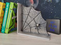 a bookend with a spider web on it and three books in front of it