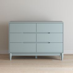 a blue dresser sitting on top of a hard wood floor next to a white wall