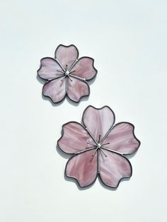 two pink flower shaped glass pieces on a white surface with one being cut in half