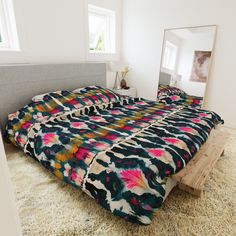 a large bed sitting in a bedroom on top of a shaggy rug next to a window