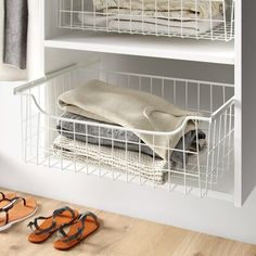 a pair of sandals sitting on top of a wooden floor next to a white shelf