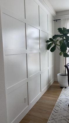 a living room with white paneling and a potted plant