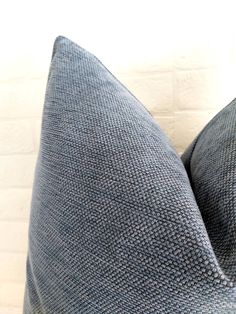 a close up view of a blue pillow on a white brick wall with a black and gray checkered design