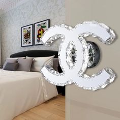 a bed room with a neatly made bed and a chanel logo on the wall