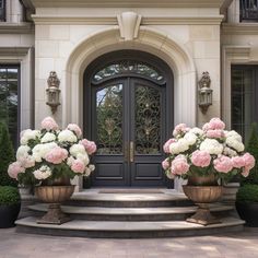 two large vases filled with pink and white flowers sit on the front steps of a house