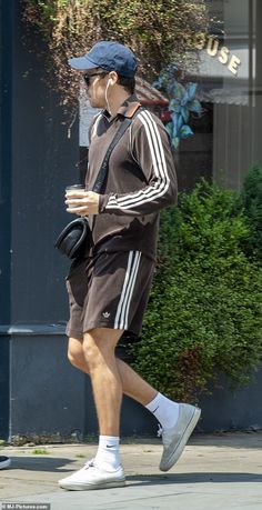 a man walking down the street with headphones in his ears and holding a coffee cup