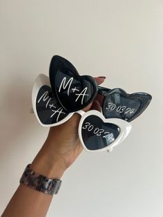 three heart shaped sunglasses with writing on them are held by a woman's hand