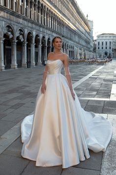 a woman in a white wedding dress standing on the ground next to an old building