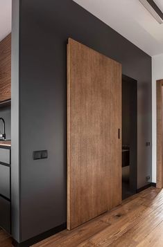 an open door in the middle of a room with wood floors and black painted walls