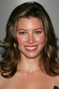 a close up of a person wearing a dress and smiling at the camera with her hair blowing in the wind