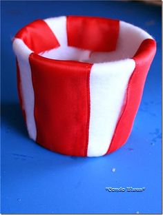 a red and white striped fabric bowl sitting on top of a blue table