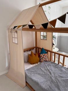 a bed with a canopy over it and pillows on the bottom bunk, in a room with white walls