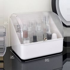 a white and black clock sitting on top of a table next to a plastic container