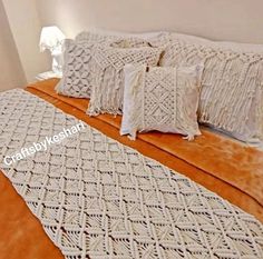 a bed with white crocheted bedspread and pillows on top of it