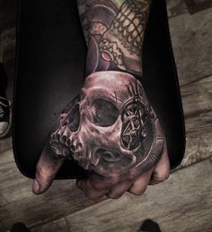 a person with a tattoo on their hand holding a clock and skull in the middle