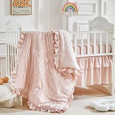 a baby crib with a pink blanket and stuffed animals on the floor next to it