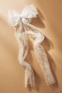 a white sheer ribbon with pearls hanging from it's side on a beige background