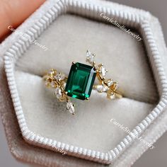 a close up of a ring with a green stone in it's center and surrounded by small white diamonds