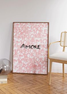 a pink and white poster sitting on top of a wooden floor next to a chair