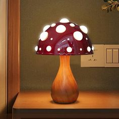 a mushroom shaped lamp sitting on top of a wooden table next to a wall mounted switch