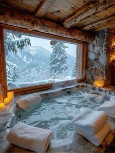 an indoor hot tub with candles lit in front of a large window overlooking the snow covered mountains