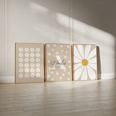 three canvases with flowers on them sitting in front of a white wall and wooden floor