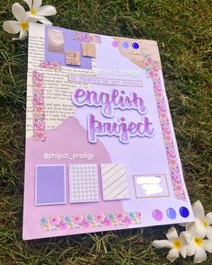 an english project book laying on the grass next to some flowers and paper with words