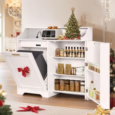 a white kitchen with a christmas tree in the corner and shelves full of spices, condiments and other items