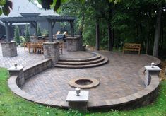 an outdoor patio with steps, seating and fire pit in the middle of it surrounded by trees