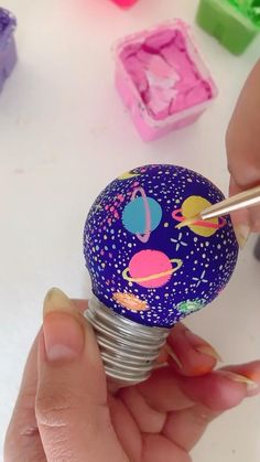 someone is painting the outer planets on a light bulb