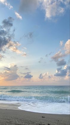 an ocean beach with waves and clouds in the sky