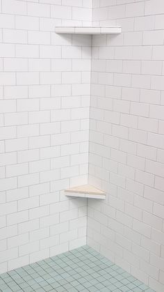 a white tiled shower stall with shelves on the wall and tile flooring around it