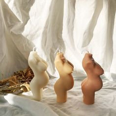 three small ceramic animals sitting next to each other on a white cloth covered tablecloth