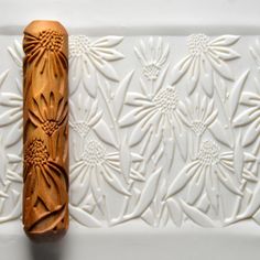 a carved wooden object sitting on top of a white tile wall next to a flower pattern