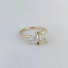 an engagement ring with two pear shaped diamonds on the side, set in yellow gold