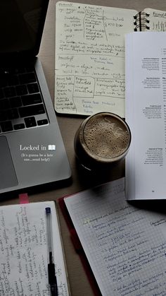 an open notebook with writing on it next to a cup of coffee and laptop computer